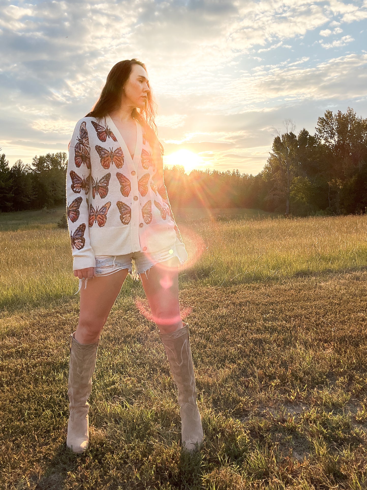 Merino Wool Cardigan in Milky White with butterflies in shades of red, blue, tangerine, and black.  Made in family owned factory in Italy. Worn with denim cutoff shorts and cowboy boots.